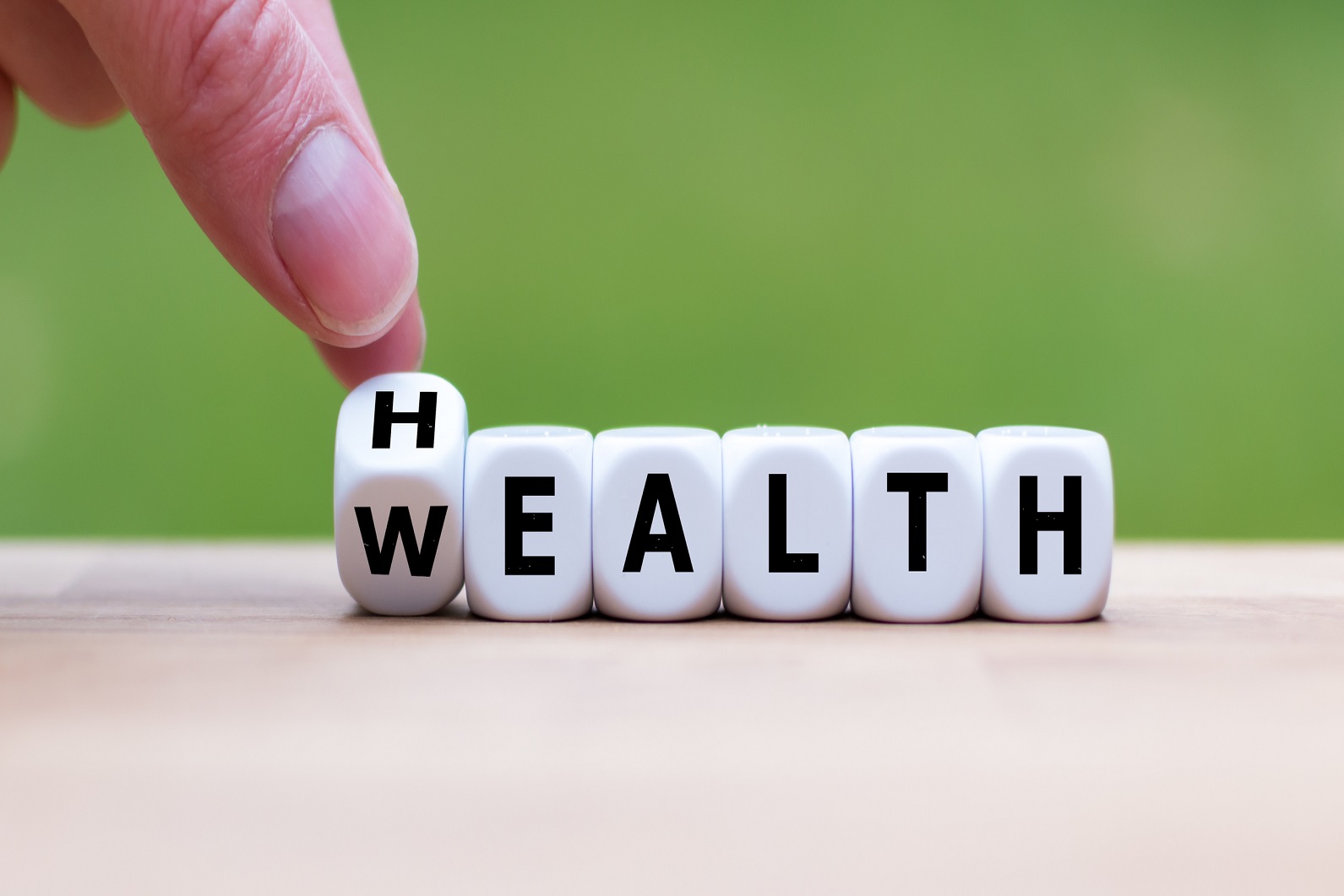 Hand turning dice changes the word "Health" to "Wealth"