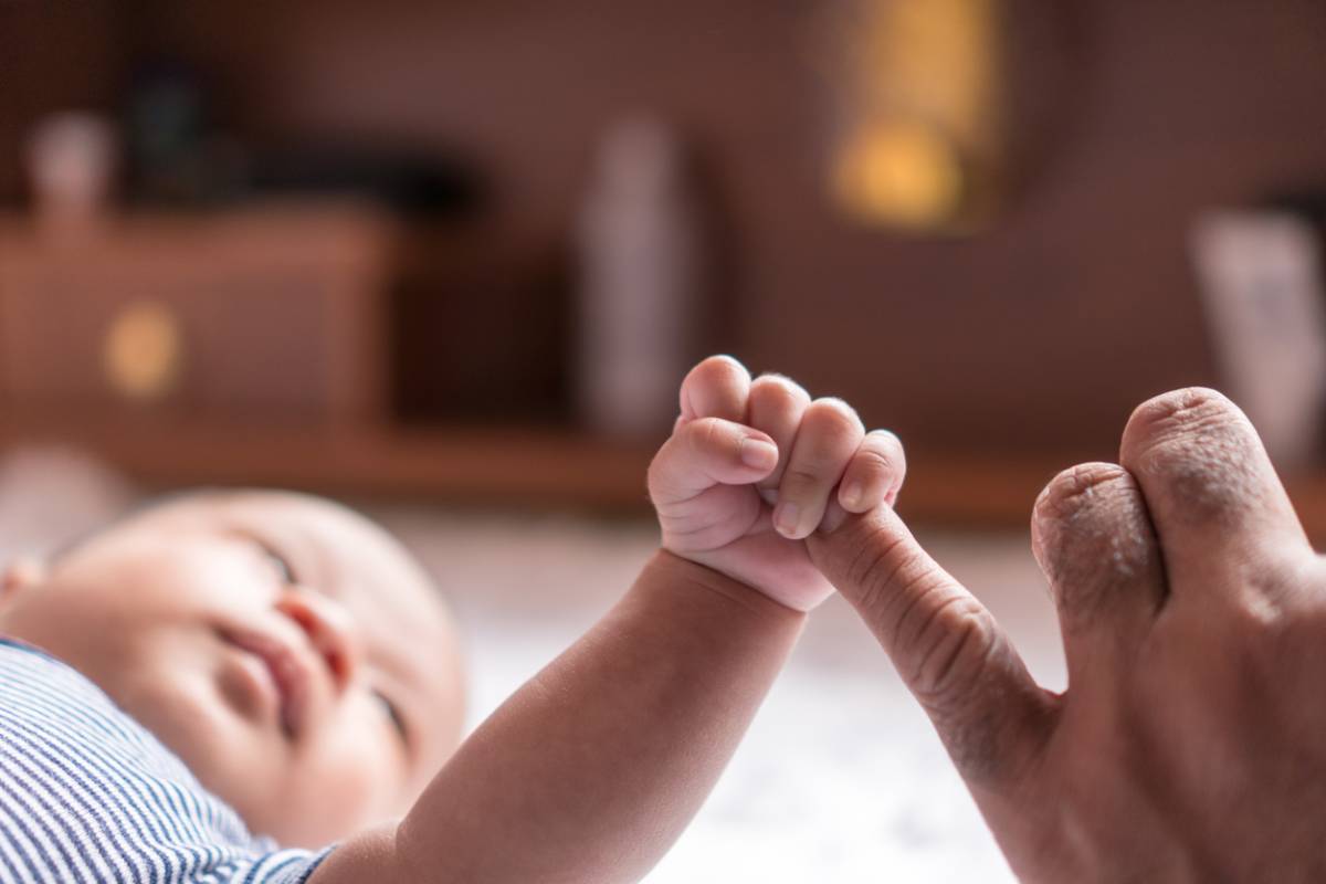 new parent with child grasping their finger